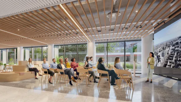 The ground floor of New Yards Haymarket with people seated, attending a presentation in the town hall area.