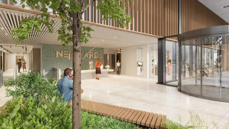 Modern reception area at New Yards Haymarket, Edinburgh, featuring a terrazzo floor, green feature wall with New Yards signage, indoor planting, and a revolving glass entrance.